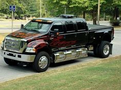 a large black truck with flames painted on it's bed is driving down the street