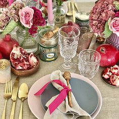 the table is set with pink flowers and silverware