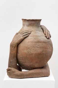 a large clay vase sitting on top of a white block