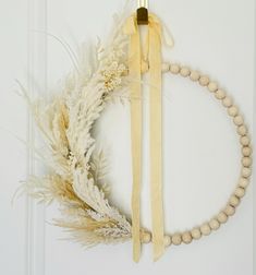 a wooden beaded necklace hanging on a door with a white feather and ribbon around it