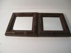 two brown framed mirrors sitting on top of a white wall