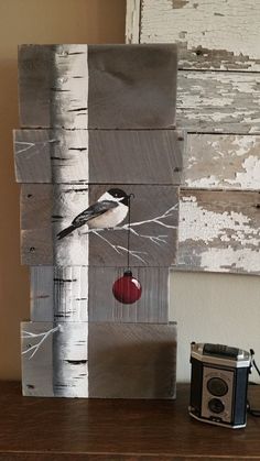 a bird sitting on top of a piece of wood with an apple hanging from it