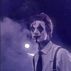 a man with his face painted like a clown wearing suspenders and a black tie