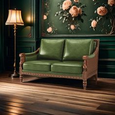 a green leather couch in front of a wall with flowers on it and a lamp next to it