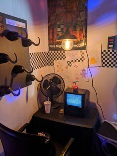 a room with a tv, fan and other items on the table in front of it