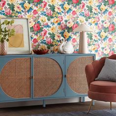 a living room with floral wallpaper and an orange chair in front of a blue cabinet