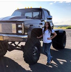 a woman standing next to a monster truck