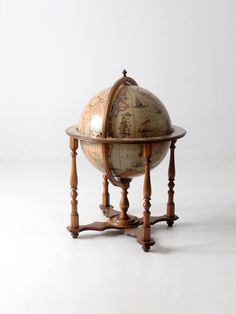 an antique wooden globe on stand with white background