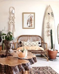 a living room filled with furniture and plants on top of a wooden table in front of a surfboard