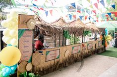 an outdoor food cart is decorated with grass and balloons