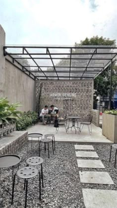 an outdoor seating area with tables and chairs on graveled ground next to a building