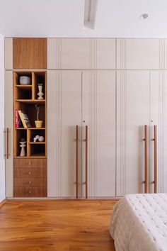 a bed sitting in a bedroom next to a white closet filled with wooden shelves and drawers