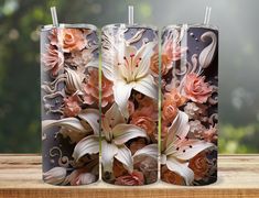 three metal canisters with flowers on them sitting on top of a wooden table