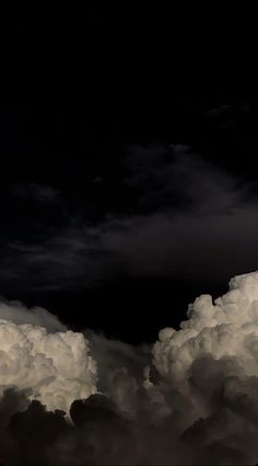 an airplane is flying high in the sky with clouds around it and dark skies above