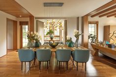 a dining room table with blue chairs and vases filled with flowers on top of it