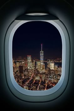 an airplane window with the city lights lit up at night