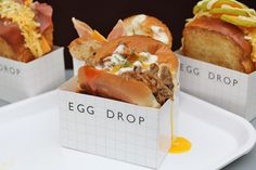 three different types of hot dogs in small boxes on a white plate with the words egg drop