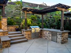 an outdoor kitchen with grill and seating area