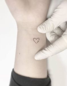 a person with a small heart tattoo on their left side of the wrist and hand