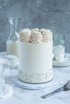 a white cake sitting on top of a table next to a fork and glass bottle