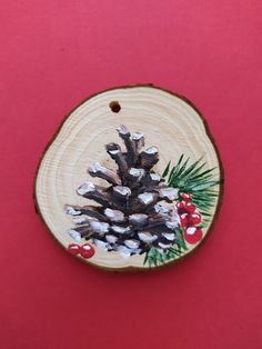 a wooden ornament decorated with pine cones and berries on a red background,