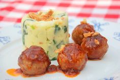 some meatballs and mashed potatoes on a white plate with a red checkered tablecloth