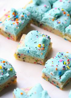 there are many pieces of cake with blue frosting and sprinkles on it