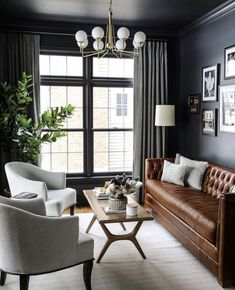 a living room with black walls and leather furniture in the center, along with pictures on the wall