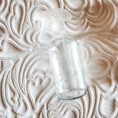 an empty glass bottle sitting on top of a bed