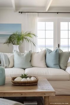 a living room filled with white furniture and lots of pillows on top of the couch