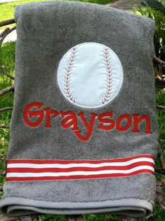 a gray towel with a red and white baseball embroidered on it sitting in the grass