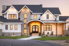 a large white house with lots of windows and lights on it's front door