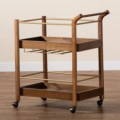 a wooden cart with two trays on wheels and one drawer open, sitting on a hard wood floor in front of a white wall