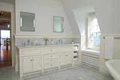 a large bathroom with two sinks and mirrors on the wall, along with white cabinetry