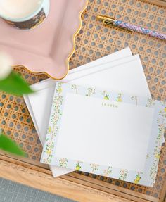 the stationery is laid out on top of the desk with flowers and a pen