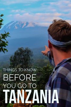 a man wearing blindfolds looking out over the mountains with text that reads things to know before you go to tanzana