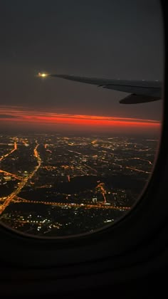 an airplane window looking out at the city lights and street lights from inside another plane