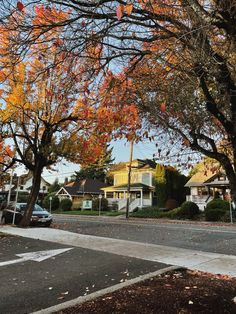 an empty street with houses and trees in the fall