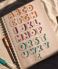 an open notebook with colorful letters and numbers on it next to a marker, pen and pencil