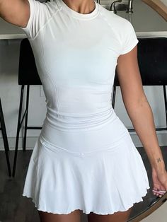 a woman in a white tennis dress taking a selfie