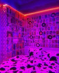 a bed with black and white spots on it in a room that has pink lights