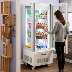 a woman standing in front of a refrigerator filled with drinks