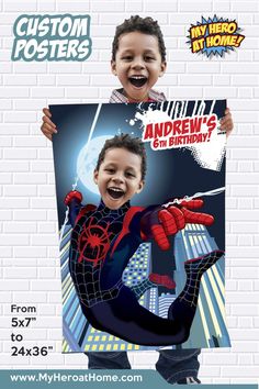 a young boy holding up a spiderman poster