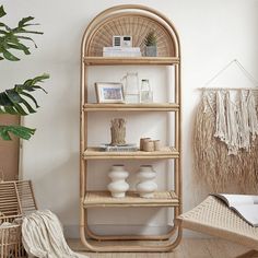 a bamboo shelf in the corner of a room with wicker furniture and potted plants