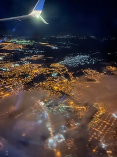 an aerial view of the city lights and airplane wing at night, taken from above