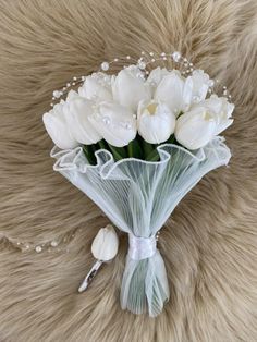 a bouquet of white flowers sitting on top of a furry surface