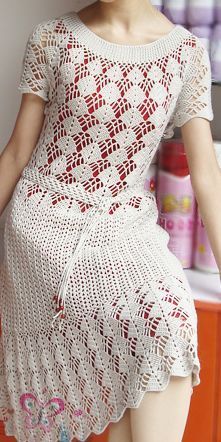 a woman sitting on top of an orange chair wearing a white crochet dress