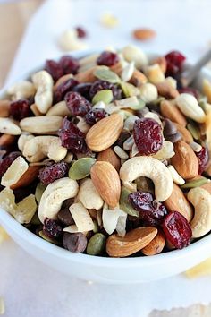 a white bowl filled with nuts and dried cranberries