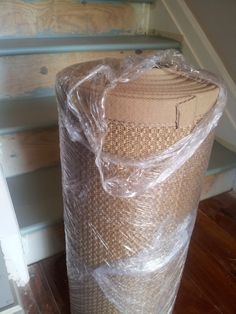 a roll of plastic wrap sitting on top of a wooden floor next to some stairs