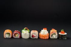 sushi rolls lined up on a black surface